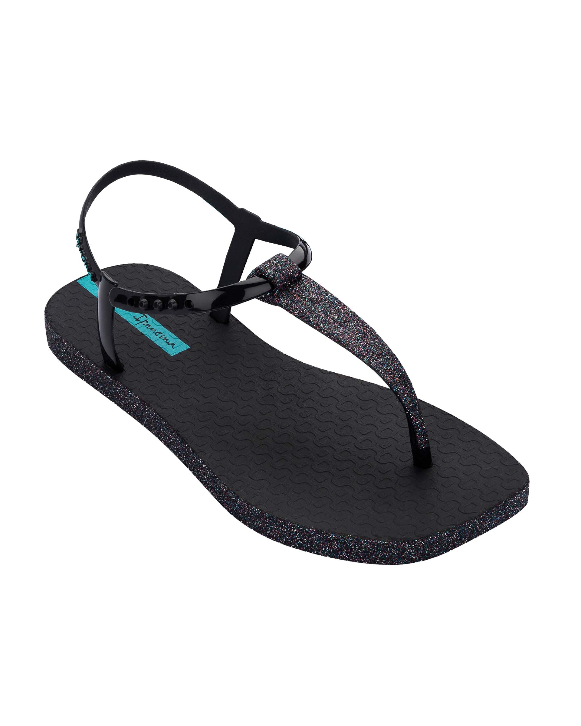 Angled view of a black Ipanema Class Edge Glow t-strap women's sandal with glitter black thong.