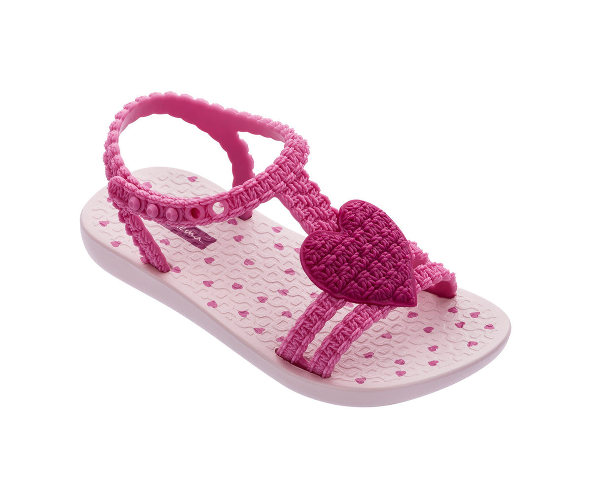 Angled view of a pink My First Ipanema Sandal with straps and a crochet heart on top.