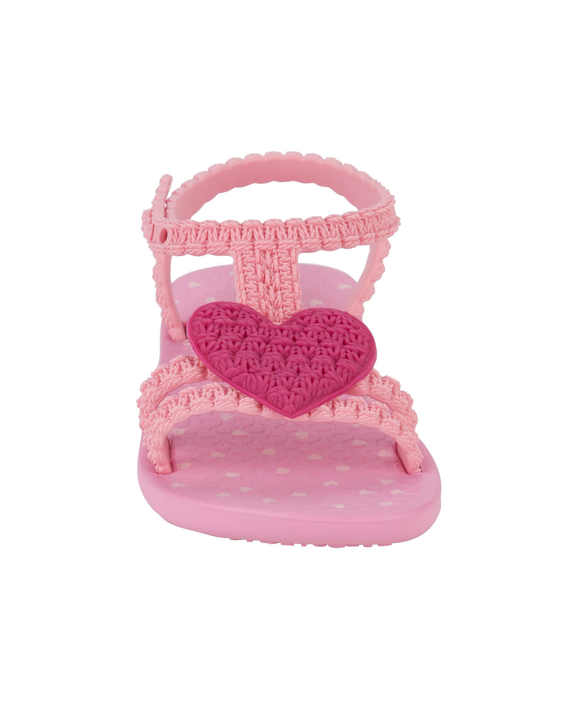 Front side view of a pink Ipanema My First Ipanema baby sandal with pink heart on top and crochet texture .