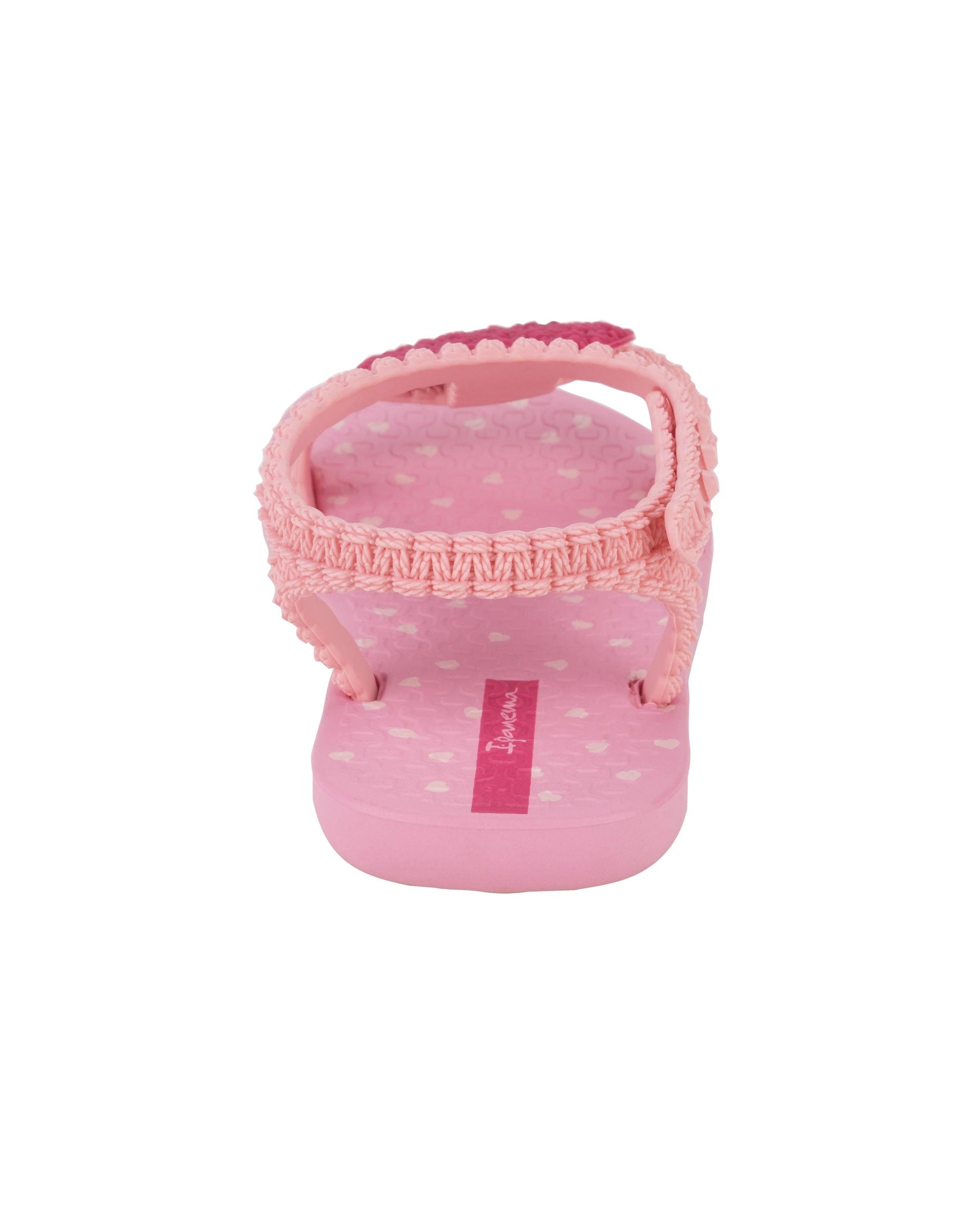 Top side view of a pink Ipanema My First Ipanema baby sandal with pink heart on top and crochet texture .