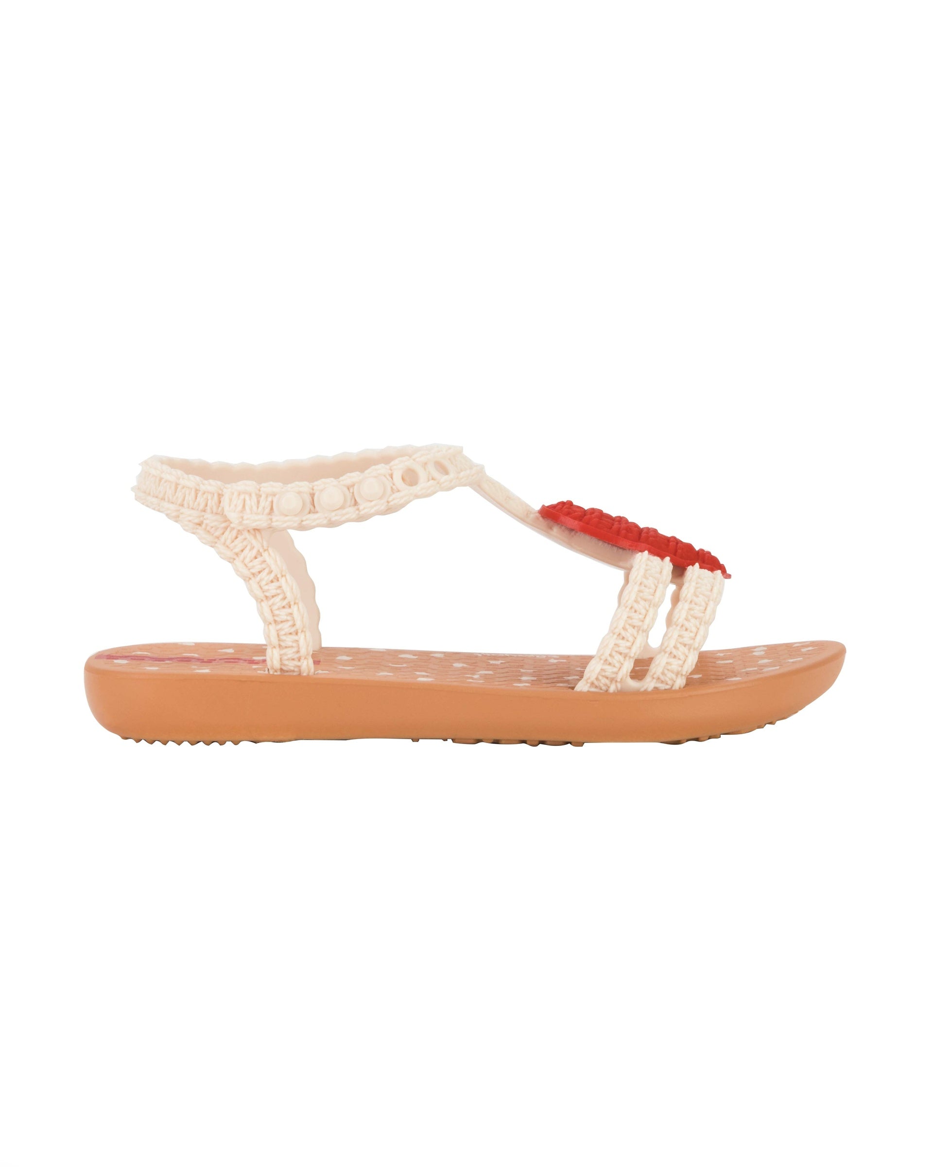 Outer side view of a beige Ipanema My First Ipanema baby sandal with red heart on top and crochet texture .