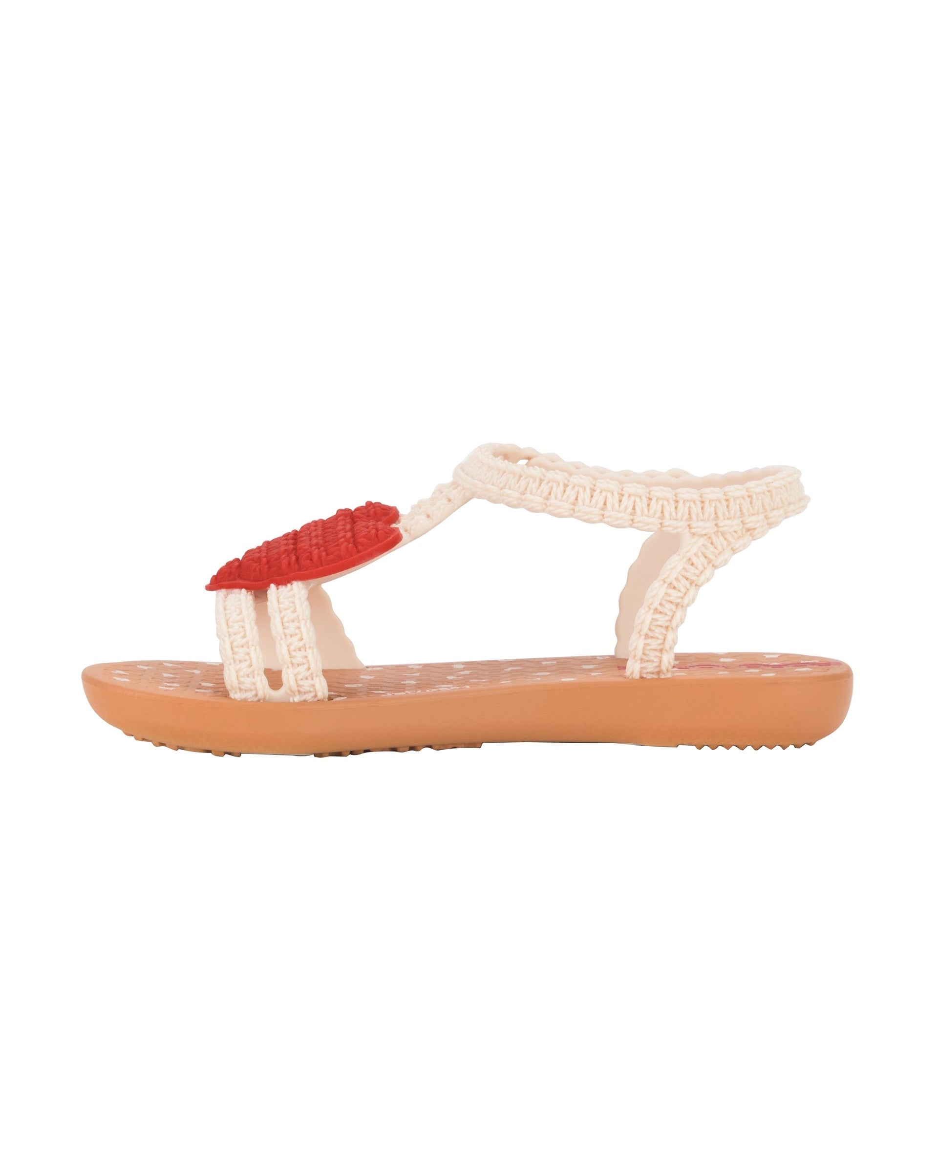 Inner side view of a beige Ipanema My First Ipanema baby sandal with red heart on top and crochet texture .