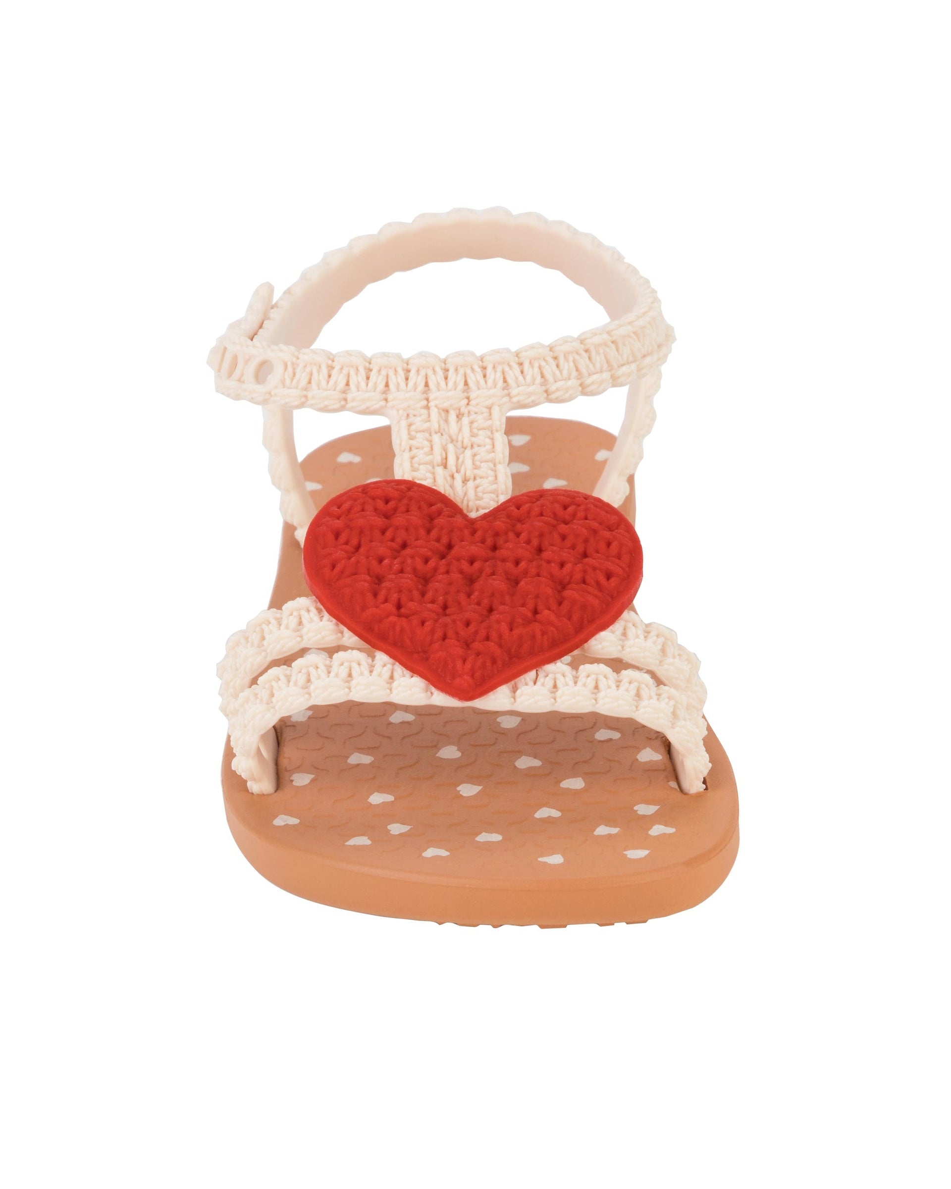 Front view of a beige Ipanema My First Ipanema baby sandal with red heart on top and crochet texture .