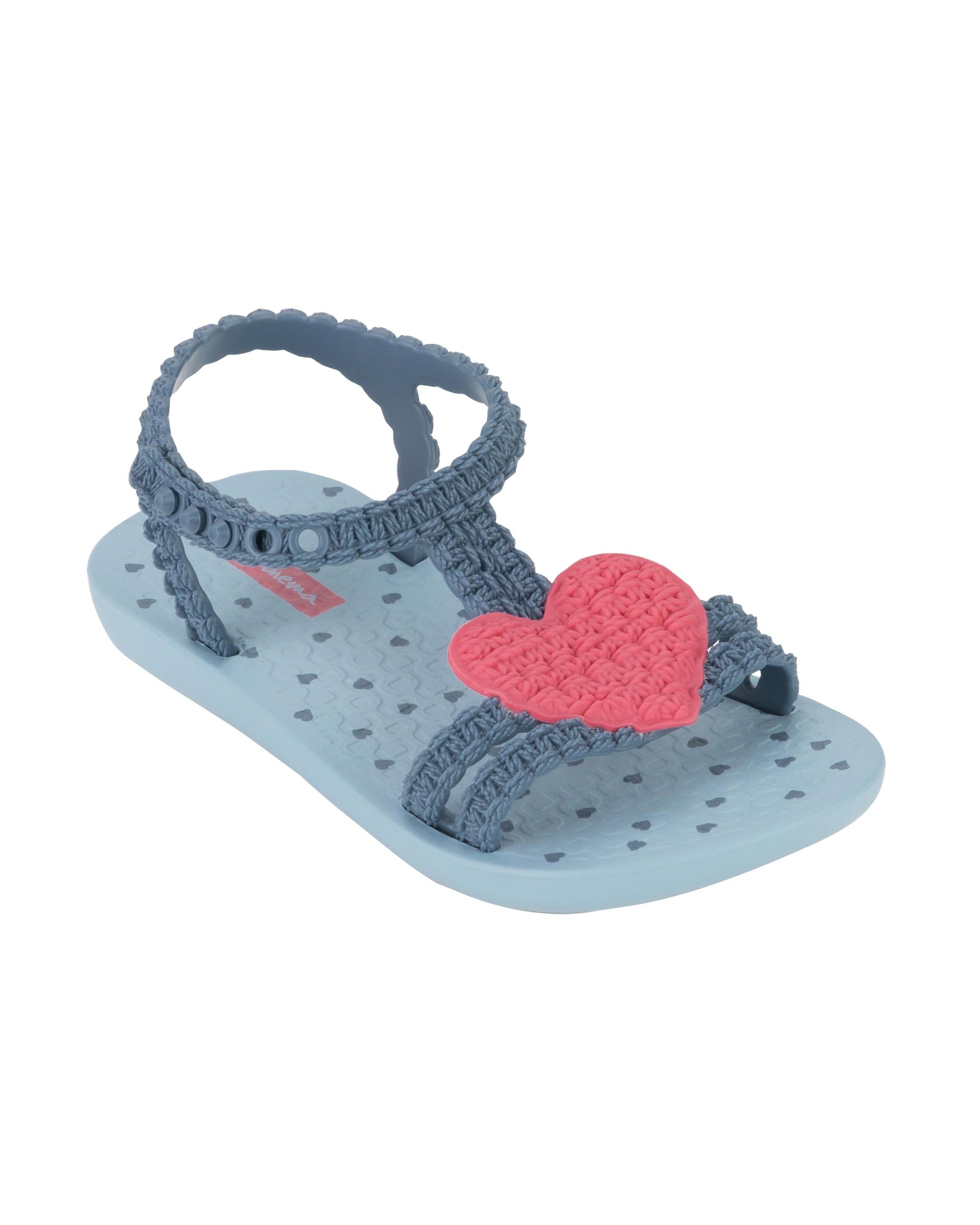 Angled view of a blue Ipanema My First Ipanema baby sandal with pink heart on top and crochet texture .