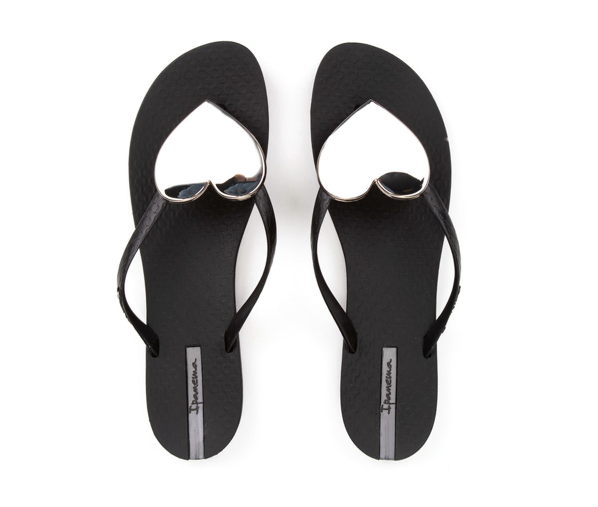 Top view of a pair of black Ipanema Wave Heart flip flops with a silver heart.