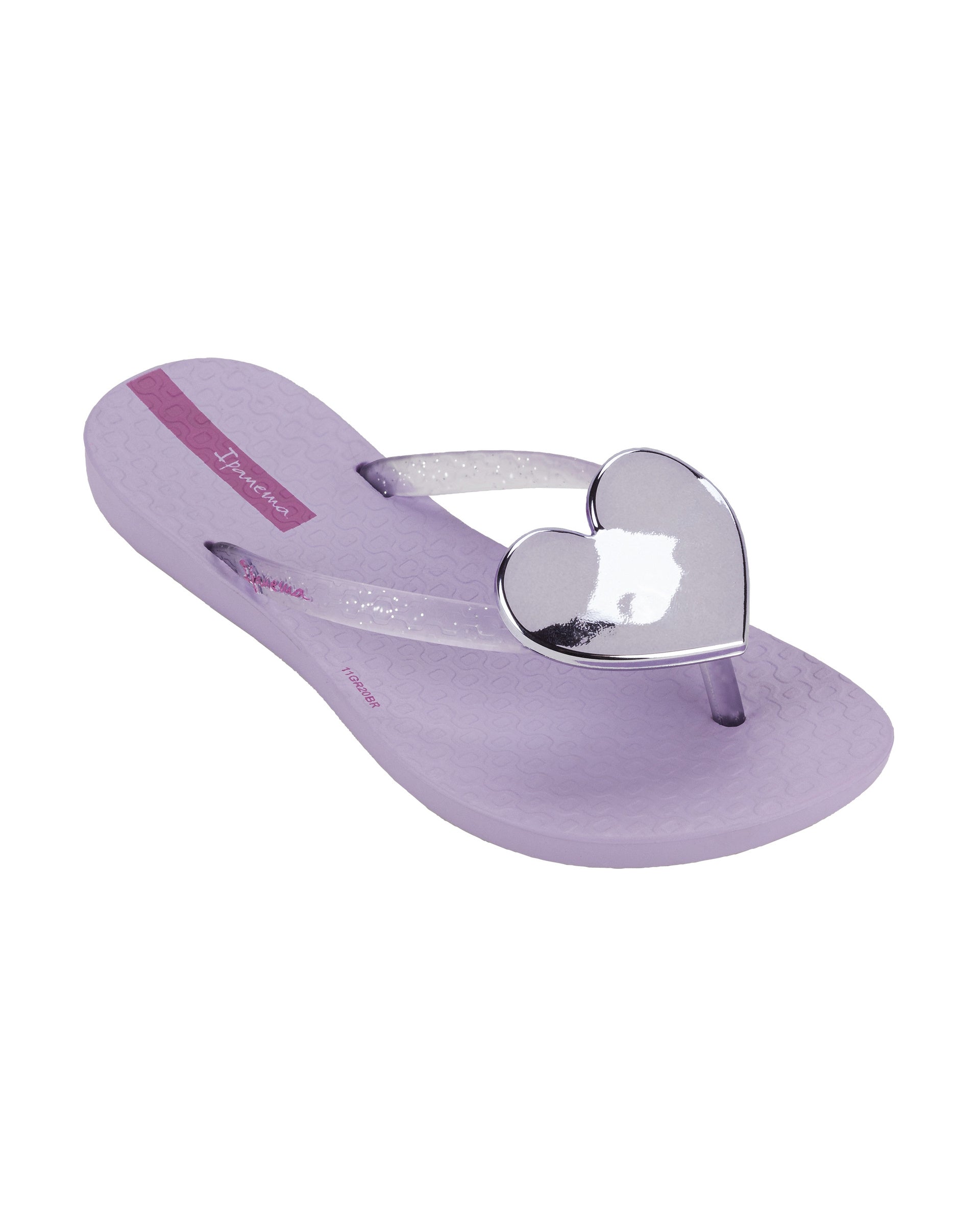 Angled view of a purple Ipanema Wave Heart kids flip flop with silver decorative heart on the clear purple upper.
