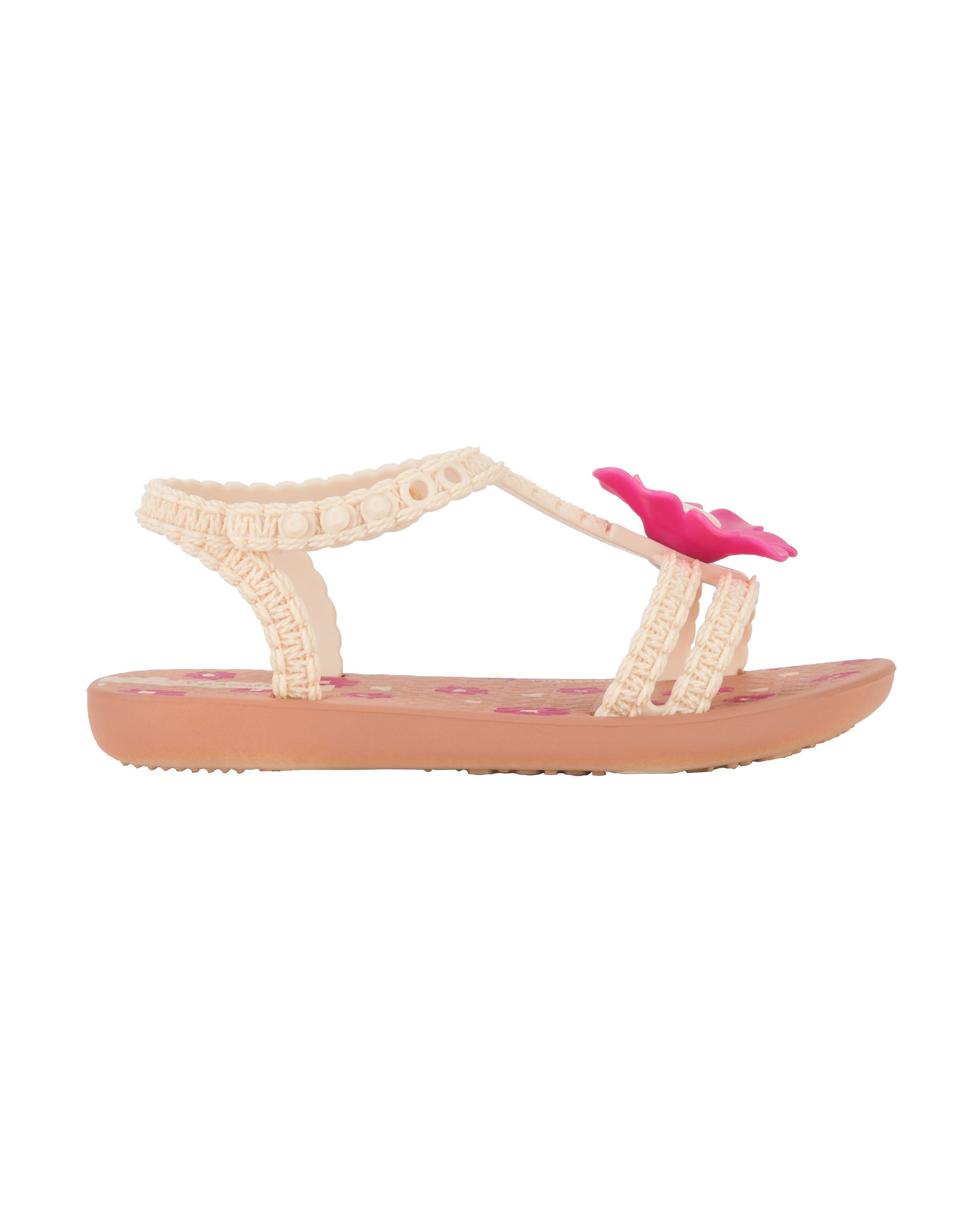Outer side view of a pink Ipanema Daisy baby sandal with pink flower on top and crochet texture .