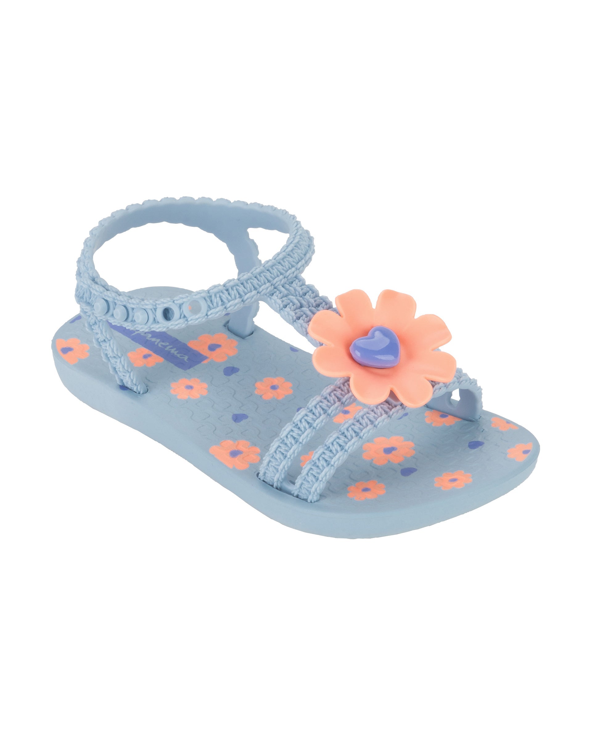 Angled view of a blue Ipanema Daisy baby sandal with pink flower on top and crochet texture .