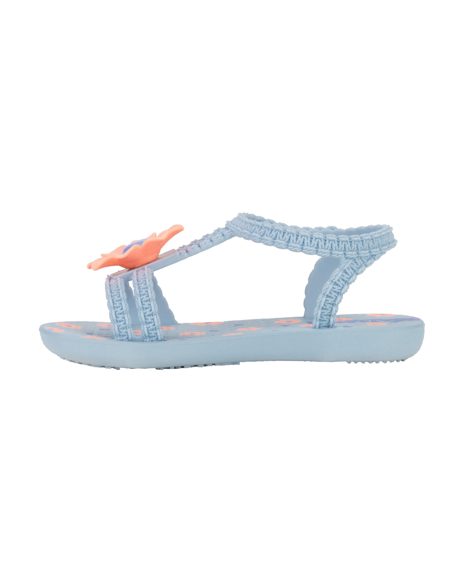Inner side view of a blue Ipanema Daisy baby sandal with pink flower on top and crochet texture .