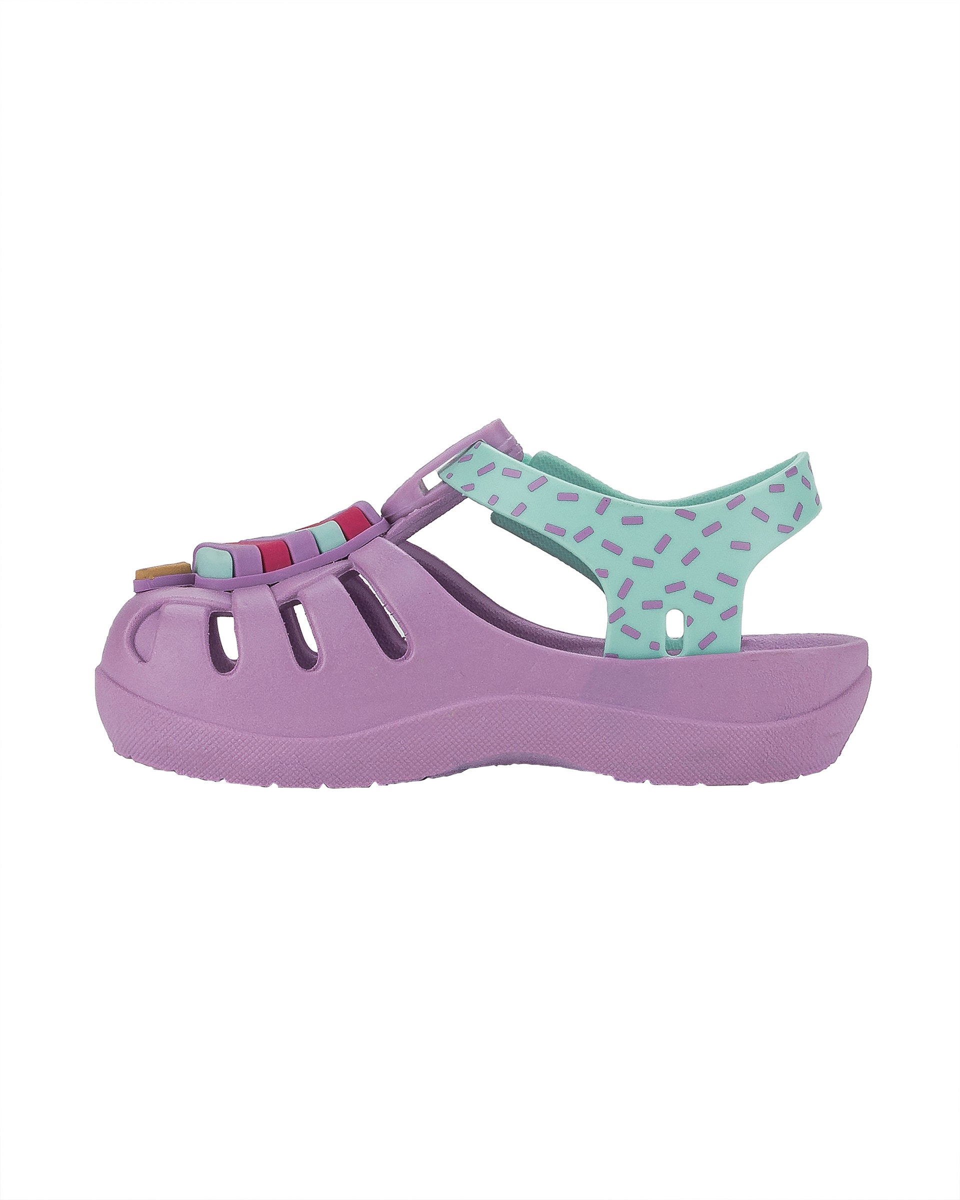 Inner side view of a purple and green Ipanema Summer baby fisherman sandal with popsicle on the upper.