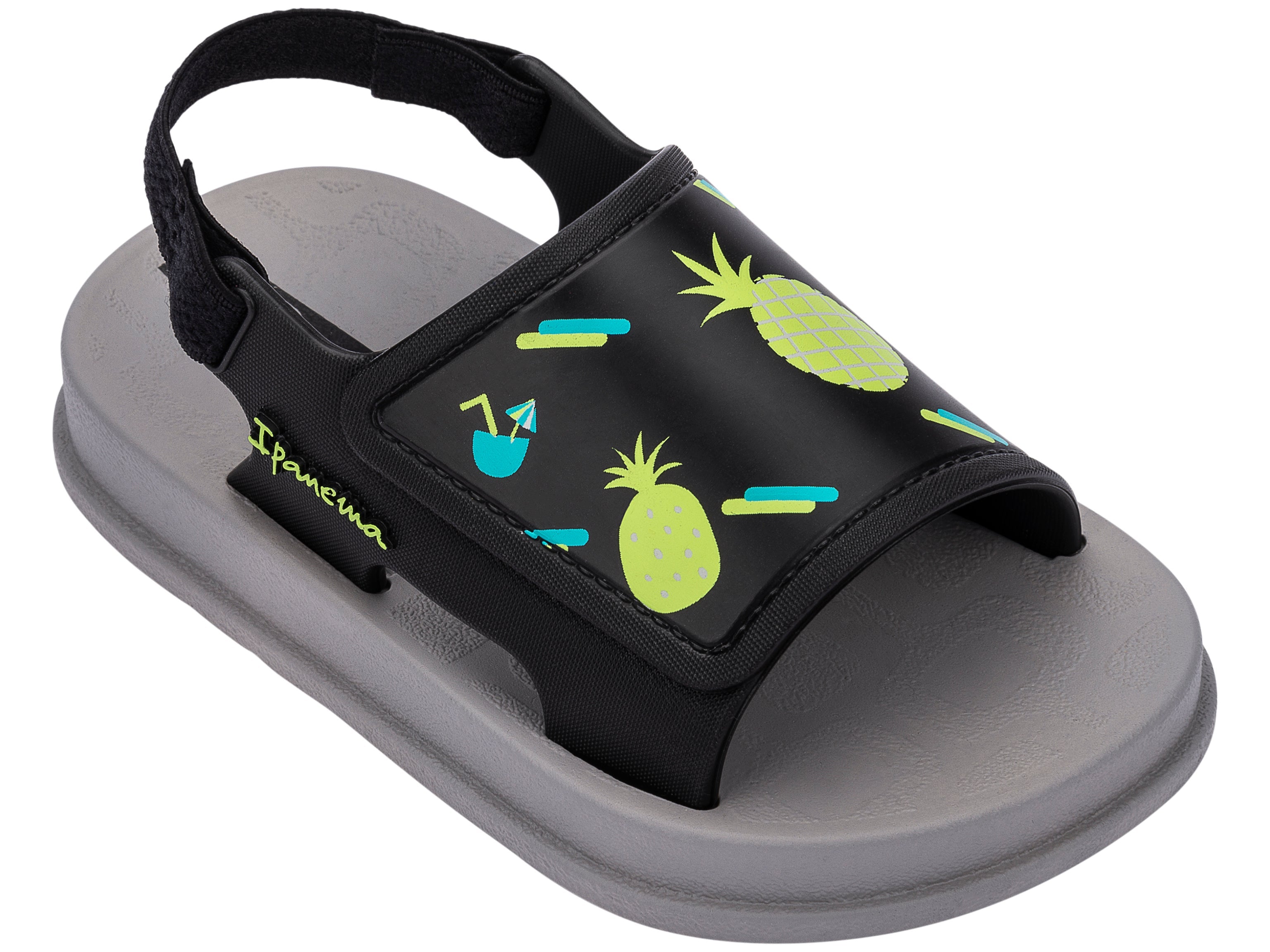 Angled view of a grey Ipanema Soft baby sandal with fruit print on the black upper.