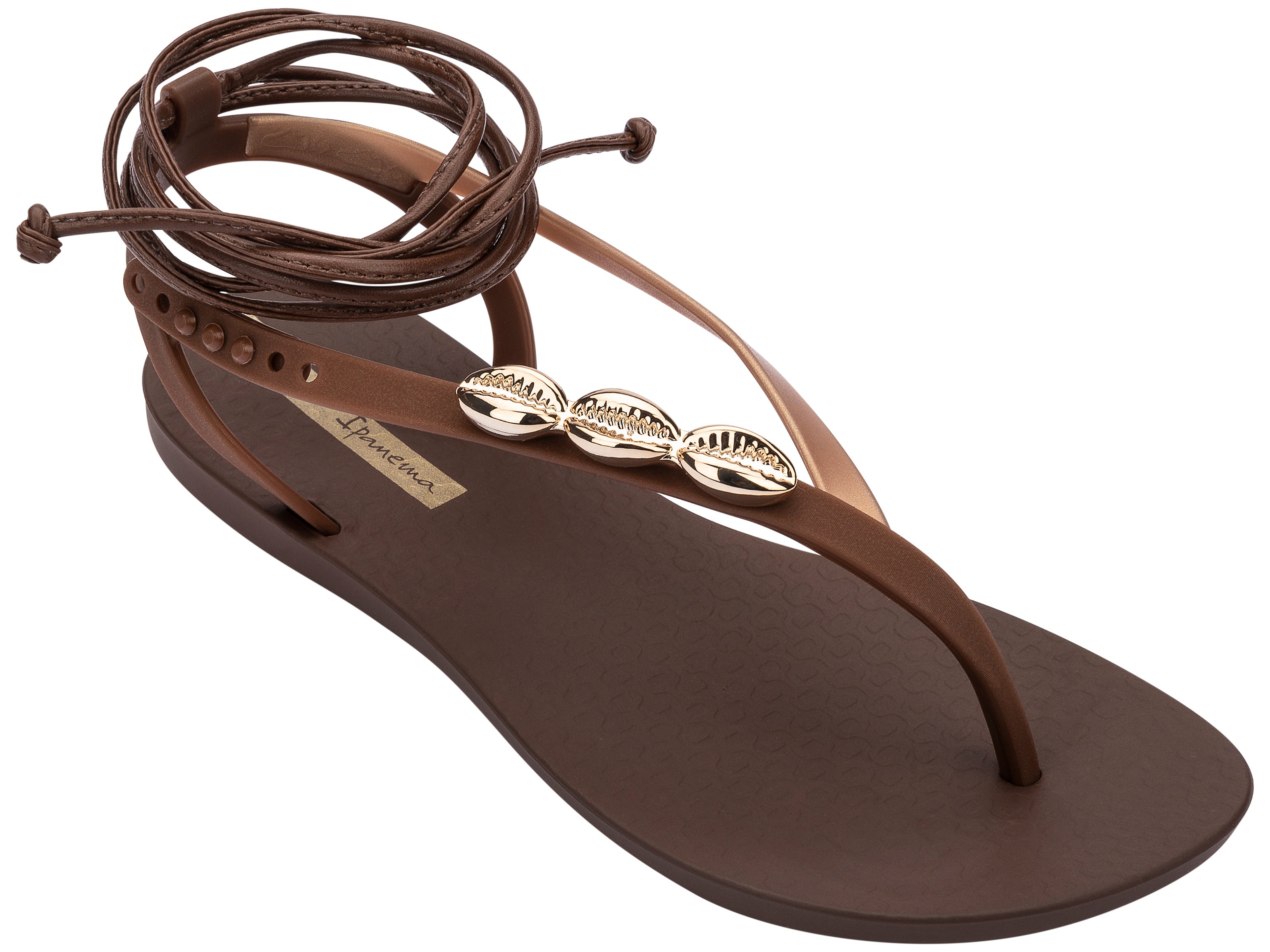 Angled view of a brown Ipanema Salty Strappy women's sandal with ankle tie up and 3 gold shells on the strap.