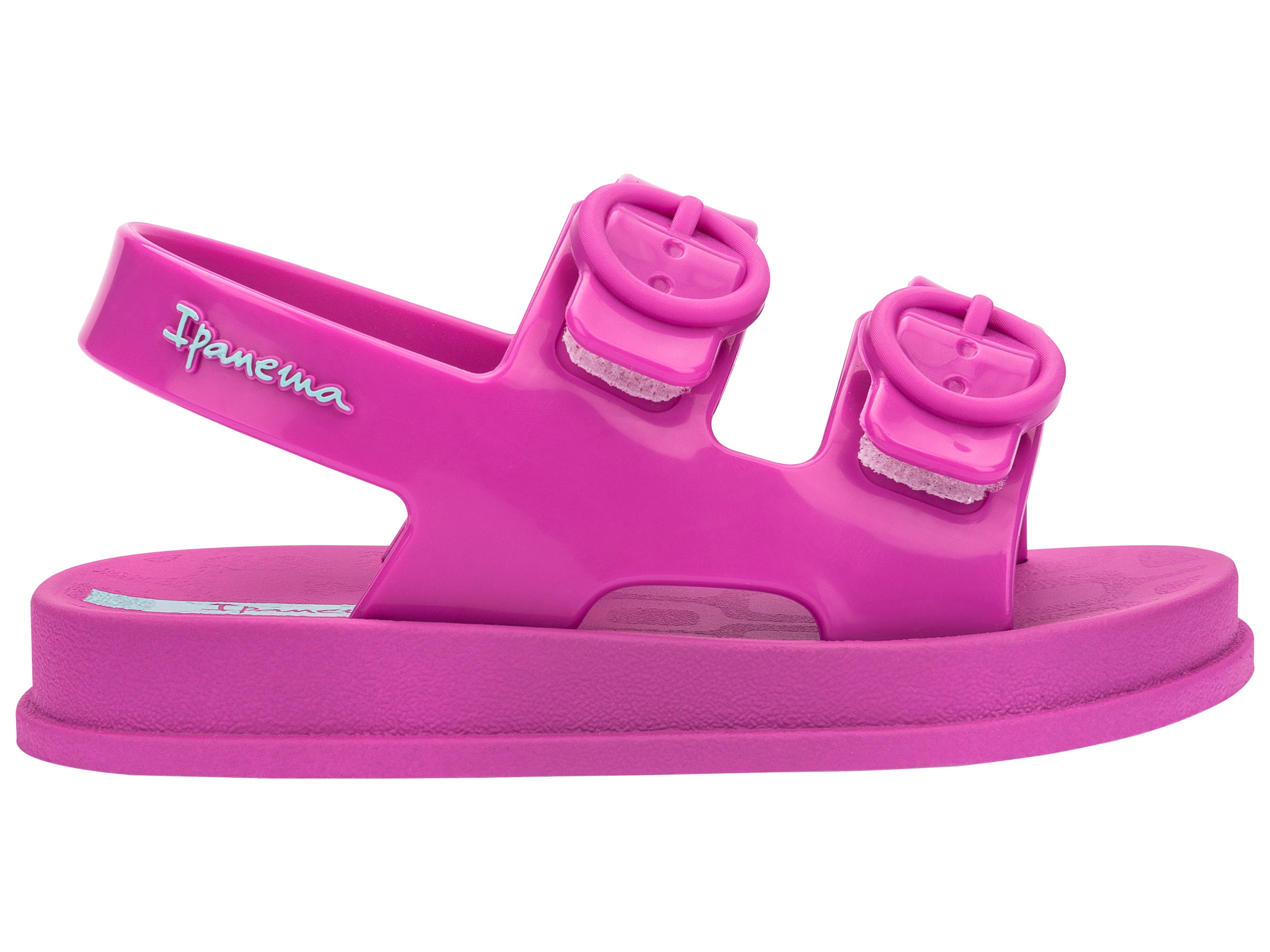 Outer side view of a pink Ipanema Follow baby sandal with two decorative buckles on the upper.